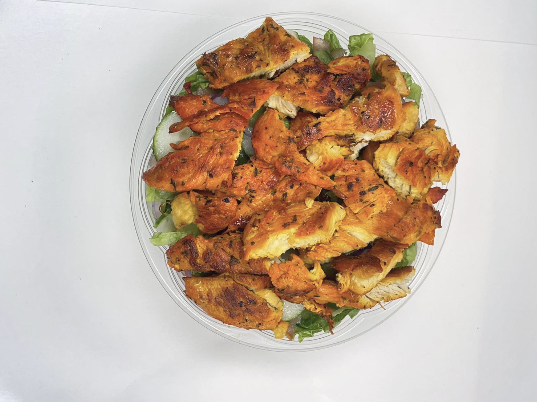 Grilled halal chicken salad with lettuce, cucumber and onion in a clear bowl