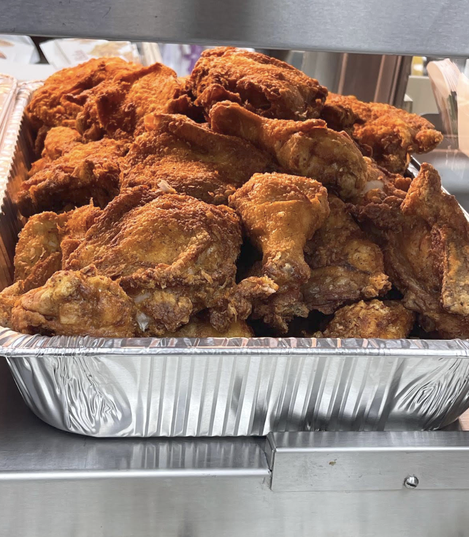 A foil pan piled high with freshly fried chicken pieces in the warmer